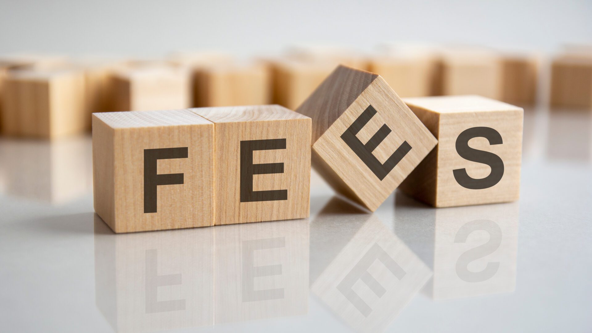 word FEES on wooden cubes, gray background